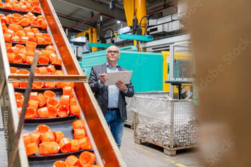 Male manager inspects plastic components in the production hall