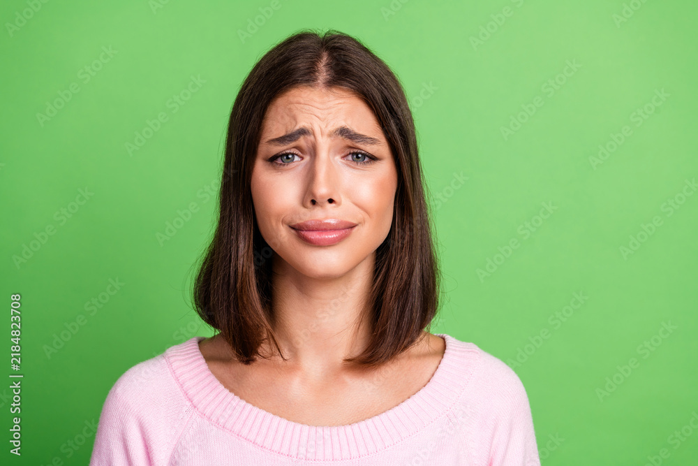 Fototapeta premium Young woman in pink sweater with a worried expression stands green background fashion style and everyday mood for advertising lifestyle beauty and promo projects