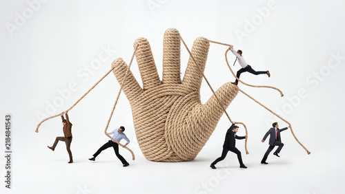 Giant rope hand controlling miniature business people through tangled strings. Concept of micromanagement  employee control and organizational pressure.