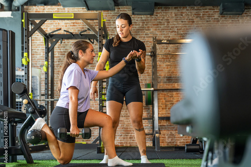 Personal trainer guiding woman performing functional gym workout