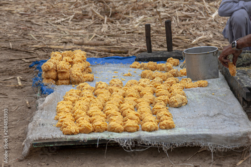 View of freshly prepared jaggery mounds displayed on a cloth during traditional cane sugar production in Multan, Punjab, Pakistan.