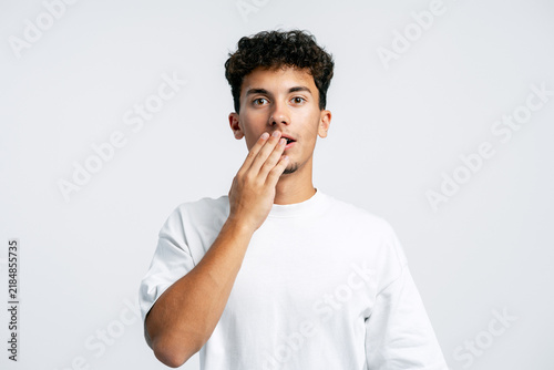 Fotografie Young man covering mouth expressing surprise disbelief
