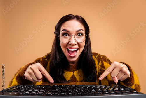 Принти на полотні Excited young woman with glasses pointing at computer keyboard while smiling and
