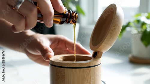 In a peaceful, sunlit kitchen, a hand delicately pours golden essential oil into a charming bamboo container. Fresh greenery surrounds, creating a soothing, organic vibe full of life and wellness.