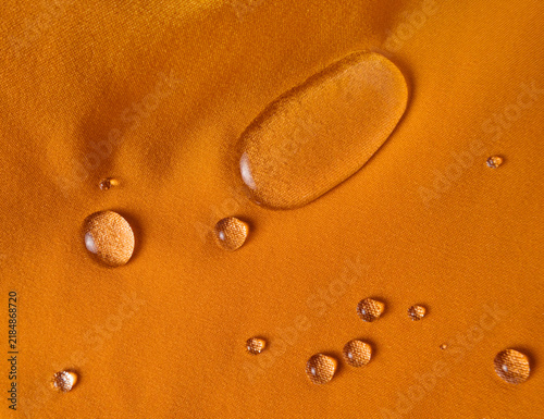 Fotografie Water drops on orange hydrophobic textile close-up