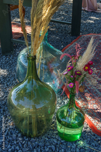 Bild auf Leinwand Large green and blue glass carboys decorated with dried pampas grass and colorfu