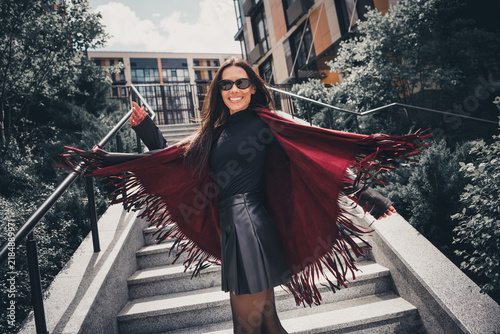 Фотография Confident woman in stylish red shawl outdoors enjoying the sun in an urban setti