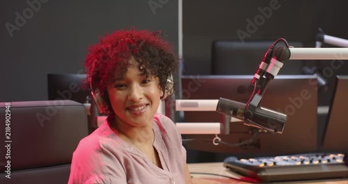 Adult African American woman starting recording, speaking into boom mic, smiling, hosting in studio