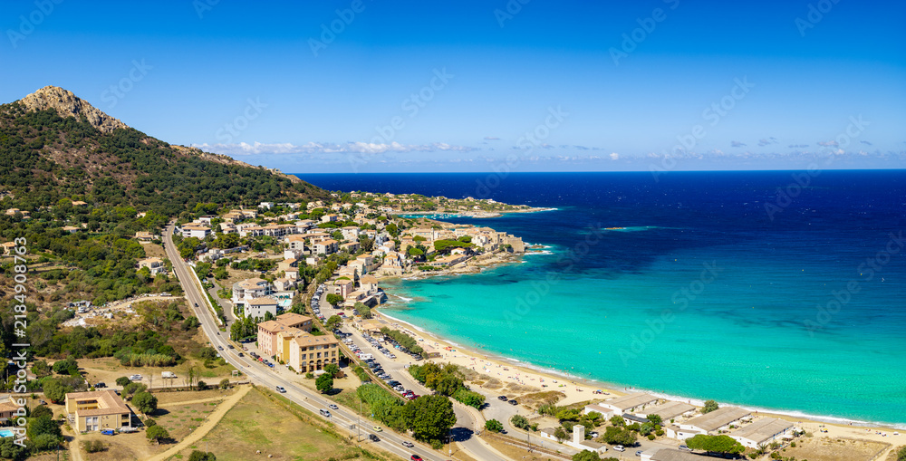 Fototapeta premium Algajola Corsica France aerial drone camera tilt down turquoise emerald sea golden sand beach resort town Balagne Ile Rousse region summer travel destination