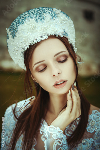 Young Woman in Traditional Russian Attire Standing by Red Brick Fortress Wall