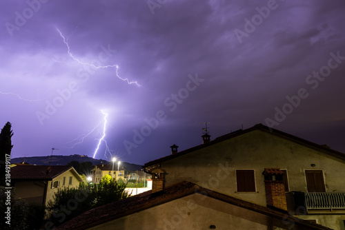 Photography Lightning striking hill behind residential houses at night