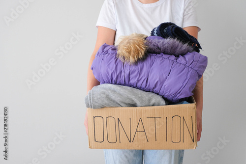 Donation box with winter clothes.  The volunteer is holding a cardboard box with warm garment.