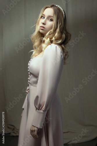 Young Woman with Blonde Hair in Pink Dress Posing in Studio