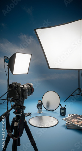Photography studio lighting setup with digital camera on tripod softboxes reflectors and light meter
