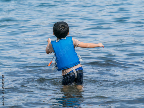 Tapety artystyczne ライフジャケットを着て海へ入る男の子の背中