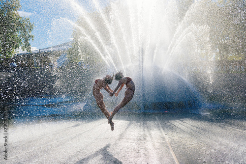 Two individuals performing synchronized acrobatic yoga jump by water