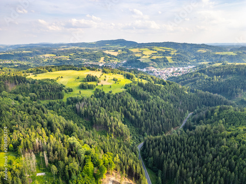Aerial view of the town of Zelezny Brod surrounded by lush green hills and dense forests in Zelezny Brod, Liberec Region, Czechia.