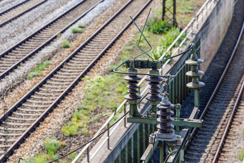 Close up of catenary overhead line disconnector switch and insulators above railway tracks, railway electrification and transport infrastructure concept