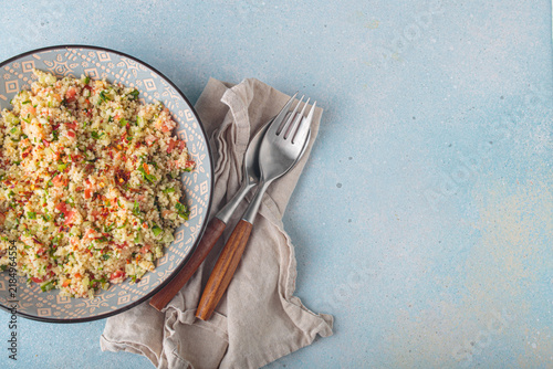 Tabbouleh salad couscous vegetables bowl Middle Eastern blue background top view copy space