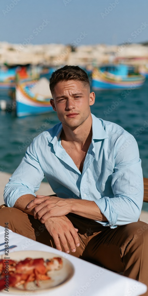 Fototapeta premium Man at a seaside table with colorful fishing boats in the harbor for travel lifestyle banner and portrait use