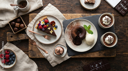 Dessert platter featuring chocolate cake, berries, and pastries arranged on wooden board.