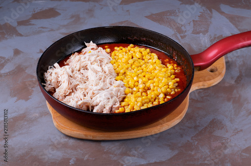 Making the filling for enchiladas, a traditional mexican dish. Adding cooked chicken and corn to a tomato-mushroom base. Step-by-step