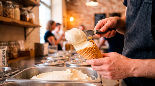 Hand putting ice cream into a cone at an ice cream shop