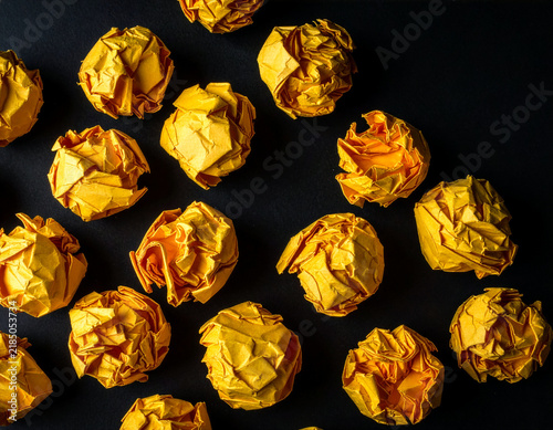 Картината върху платно Top View of Scattered Yellow Crumpled Paper Balls on Black Background
