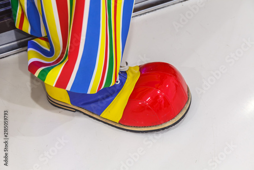Brightly striped trousers hug a red clown shoe