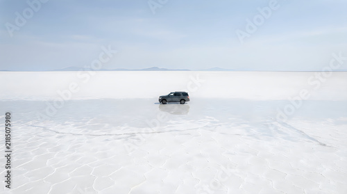 Suv driving on vast white salt flat desert landscape