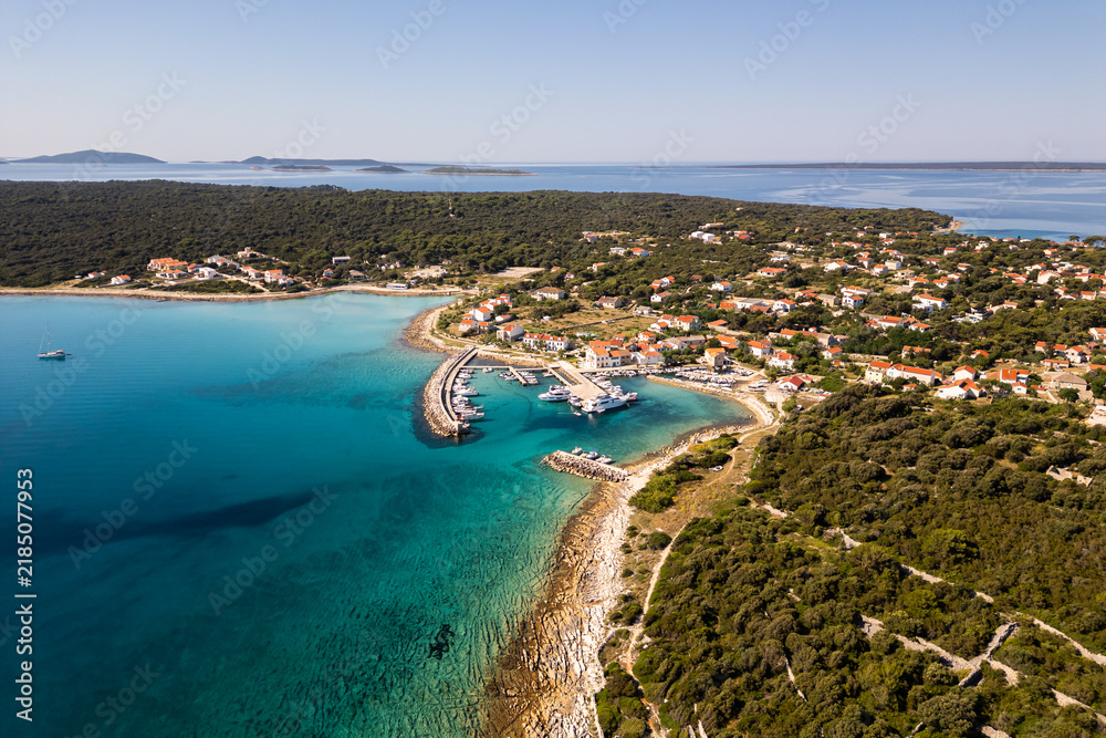 Fototapeta premium Aerial drone panorama of the western part of Silba Island, Croatia, surrounded by the crystal-clear Adriatic Sea. The picturesque coastal village, turquoise shoreline and Mediterranean vegetation