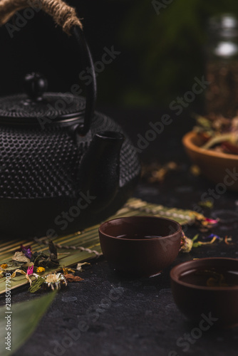 Traditional Asian tea in black cast iron vintage teapot with two cups on dark stone table, top view. Asian tea ceremony arrangement set