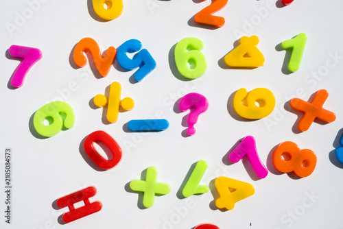 Colorful plastic numbers and math symbols with hard light shadows on white background for education and learning concept