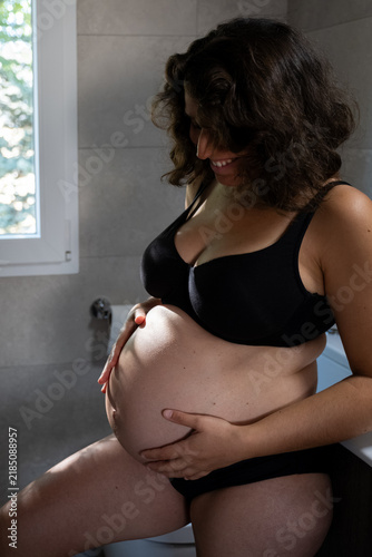 Картината върху платно Pregnant woman feeling her baby bump in the bathroom, anticipating motherhood