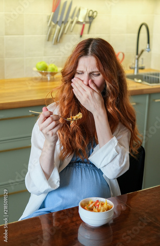 Картината върху платно Pregnant woman experiencing nausea and food aversion while eating a meal at home, illustrating morning sickness and common pregnancy symptoms