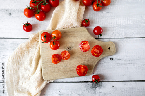 Картината върху платно Fresh cherry tomatoes whole and halved on a wooden cutting board