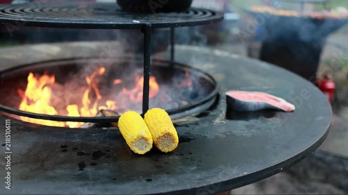 Corn grilling by open flame at a cooking event in an outdoor setting