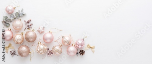Christmas banner with pink and rose gold baubles and copy space on white background