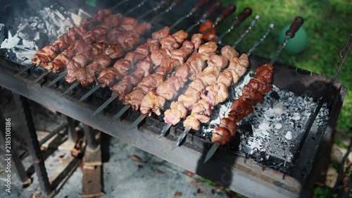 Meat skewers grilling on charcoal barbecue. Shashlik roasting over hot coals with smoke. Traditional outdoor cooking of kebab on brazier grill.