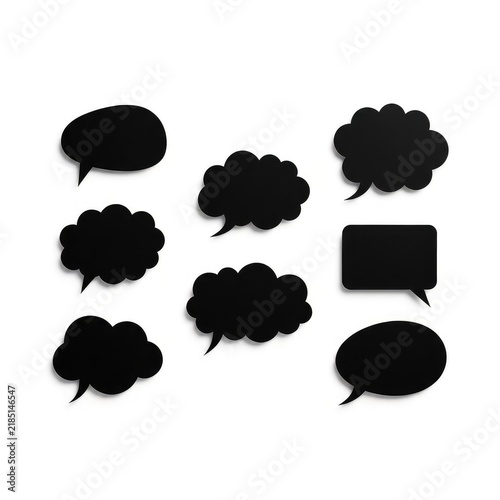 A minimalist composition featuring various solid black speech bubbles and communication clouds arranged neatly on a clean white background, cloud, message, talk