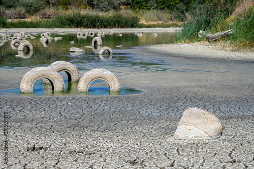 Konstfotografi A dry lakebed features numerous tires partially submerged in the cracked earth