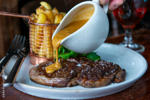 Delicious Steak Served With Golden Sauce and Crispy Fries in a Cozy Restaurant Setting