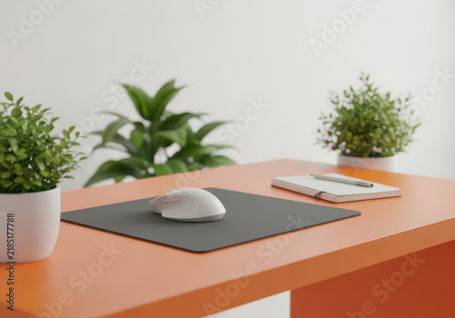 Modern wireless computer mouse on a dark pad at a bright orange desk