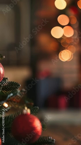 A cozy scene featuring a decorated Christmas tree adorned with vibrant red ornaments, set against a backdrop of a softly lit fireplace and festive string lights, evokes a serene holiday mood.