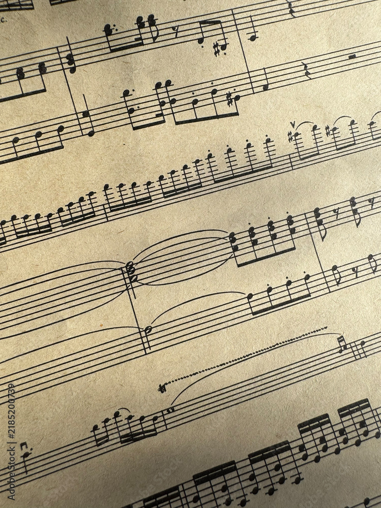 Fototapeta premium Close up of sheet music with musical notes and textured paper. Musical notes on sheet music, clear details of composition. Black notes, musical score, sheet music, musical notation, classical music