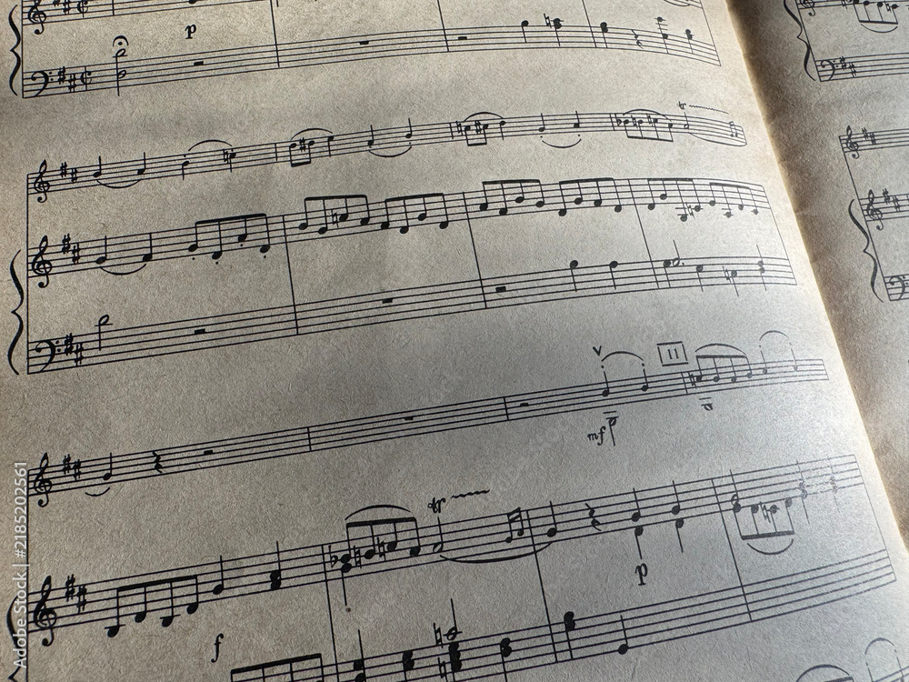 Fototapeta premium Close up of sheet music with musical notes and textured paper. Musical notes on sheet music, clear details of composition. Black notes, musical score, sheet music, musical notation, classical music