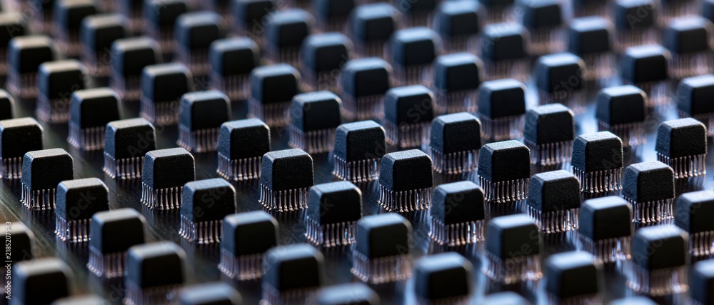 Fototapeta premium Rows of black electronic components on circuit board with shallow depth of field
