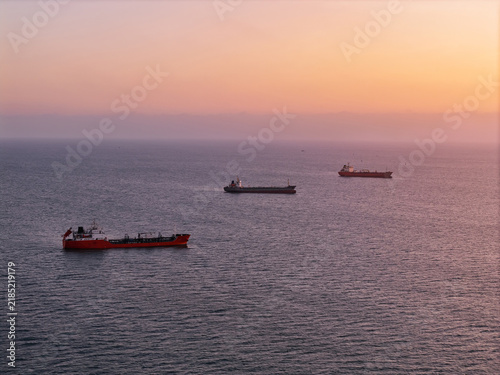 Foto Aerial view Tanker ships with oil floating idle on calm ocean at sunset, waiting