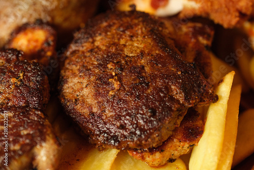 Macro close-up of juicy grilled minced meat patties with a crispy brown crust served alongside golden french fries. Concept of hearty dining, grilled meat dish, barbecue cuisine, homemade burger patti