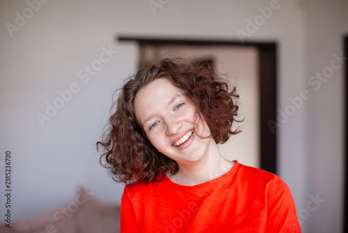 Фотография Young cheerful woman with curly brown hair smiling at home